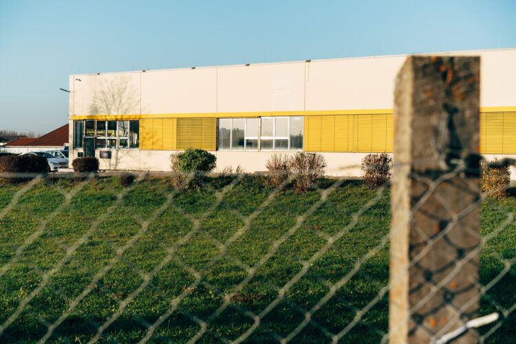 Een bedrijfspand achter een hek aan de rand van een industrieterrein