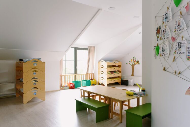 Een lege, lichte groepsruimte van een kinderdagverblijf met houten meubels en speelgoed