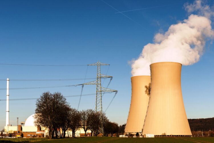 Koeltorens van een kerncentrale met stoomwolken tegen een blauwe lucht
