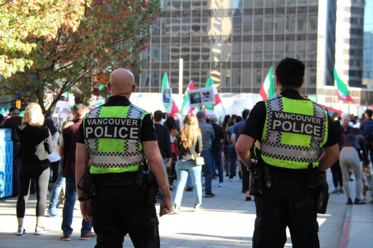Twee agenten van de politie van Vancouver, van achteren gezien, bij een demonstratie in de stad