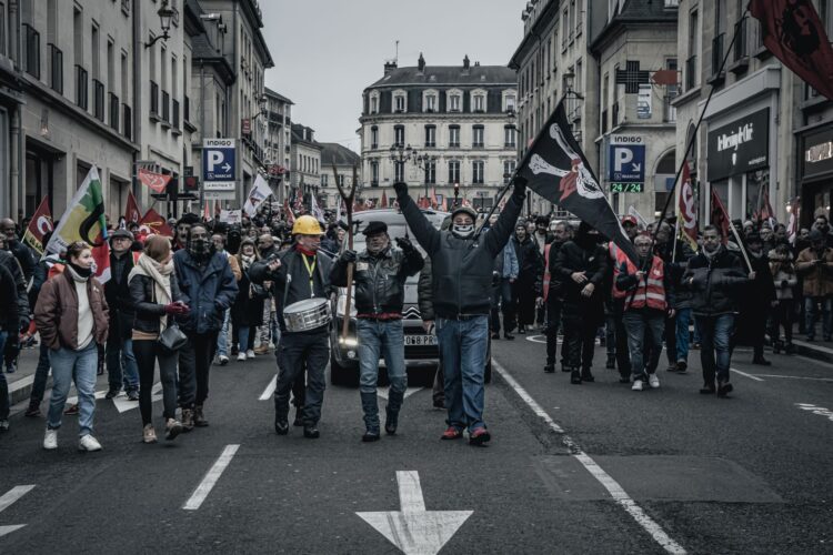 Demonstranten met vakbondsvlaggen lopen door een Franse winkelstraat