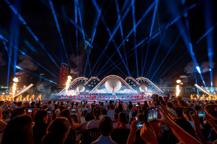 Publiek bij een avondconcert met een grote lichtshow boven het podium
