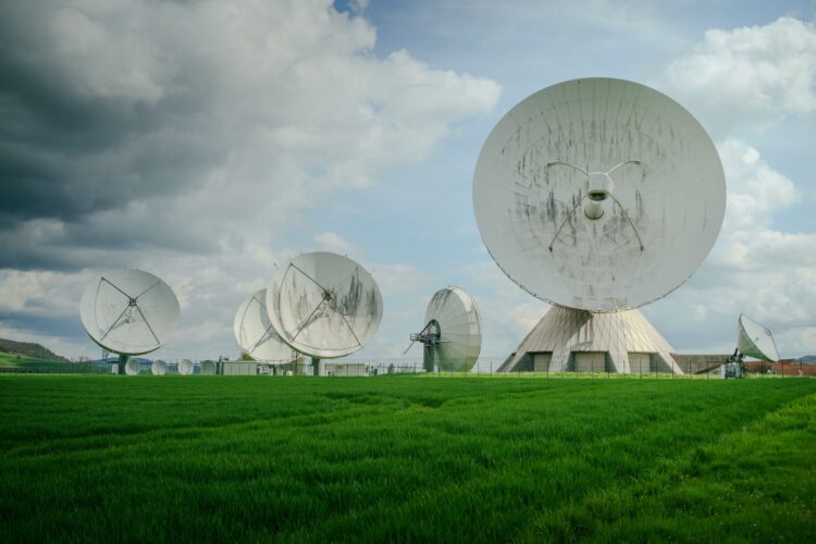 Grote witte schotelantennes van een grondstation in een groen veld