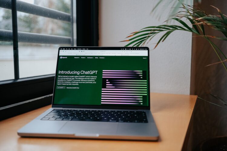 Laptop op een bureau bij het raam met de introductiepagina van ChatGPT op het scherm