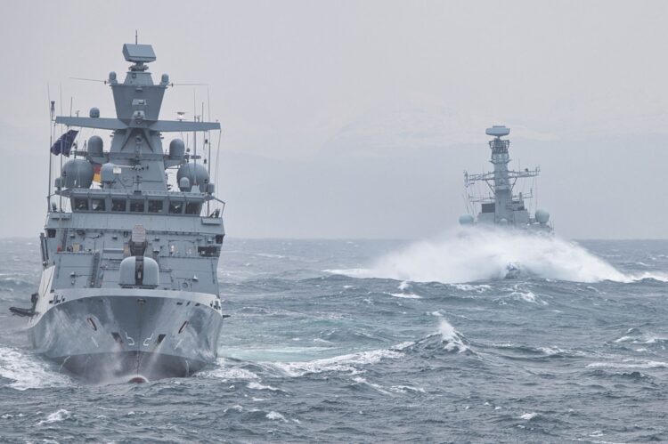 Twee grijze marineschepen van de Duitse marine varen door woelige zee