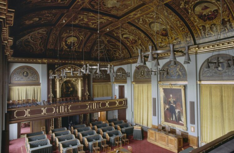 Vergaderzaal van de Eerste Kamer in Den Haag met gewelfd plafond en lege banken