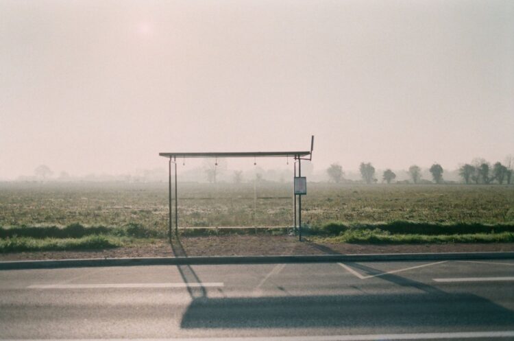 Lege bushalte langs een landweg met weilanden in de mist